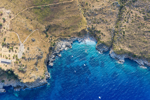 Aerial view of Riserva Naturale Orientata dello Zingaro with turquoise waters rocky cliffs and small boats along the coastline in San Vito Lo Capo Sicilia Italy. Aerial view of Riserva Naturale Orientata dello Zingaro with turquoise waters rocky cliffs and small boats along the coastline in San Vito Lo Capo Sicilia Italy.