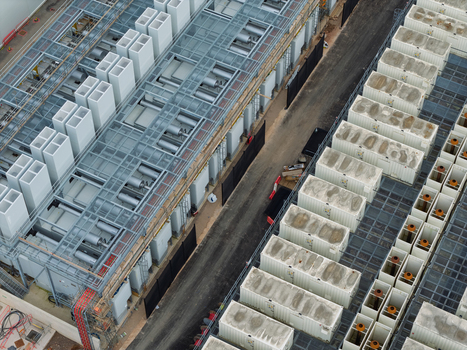 Aerial view of a data center facility featuring rows of modular cooling units and industrial infrastructure with metal framework and concrete surfaces in the United Kingdom.
