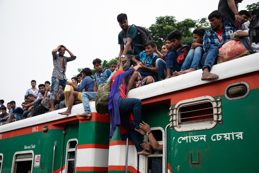 Dhaka Bangladesh 15 June 2018 View of people crowded on the roof of a train at Airport Railway Station with a woman being helped to climb up during the holiday rush. Dhaka Bangladesh 15 June 2018 View of people crowded on the roof of a train at Airport Railway Station with a woman being helped to climb up during the holiday rush.