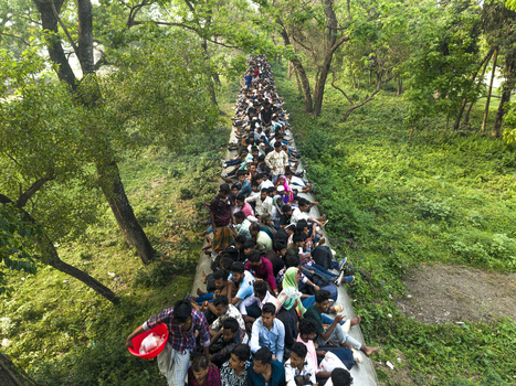 Dhaka Bangladesh 27 March 2026 Aerial view of a dense crowd surging along a narrow path a vibrant river of humanity cutting through the verdant green landscape. Dhaka Bangladesh 27 March 2026 Aerial view of a dense crowd surging along a narrow path a vibrant river of humanity cutting through the verdant green landscape.