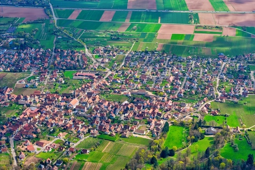 Aerial view of the charming village nestled amid patchwork fields and vineyards a tapestry of earth tones contrasted by vibrant greens Kintzheim Grand Est France.