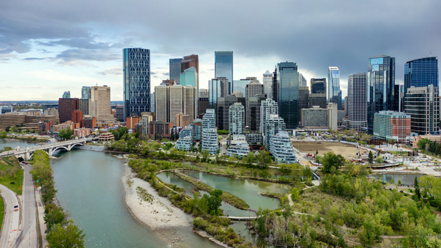 Aerial view of the Calgary skyline featuring the Bow River Prince s Island Park and modern skyscrapers under a cloudy sky in Calgary Alberta Canada.
