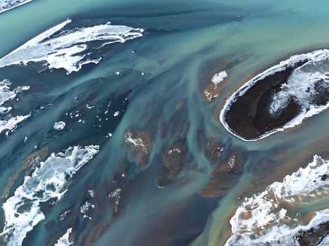 Aerial view of a glacial river with intricate braided channels sediment rich turquoise water and patches of ice and snow in Iceland. Aerial view of a glacial river with intricate braided channels sediment rich turquoise water and patches of ice and snow in Iceland.