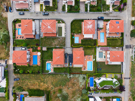 Aerial view of modern residential houses with red tiled roofs private swimming pools and green gardens in a suburban neighborhood in Lozenets Burgas Bulgaria.
