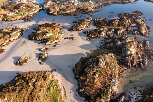 Aerial view of the rugged coastline and sandy beaches of Kincasslagh featuring rocky outcrops tidal inlets and green coastal terrain in Kincasslagh County Donegal Ireland. Aerial view of the rugged coastline and sandy beaches of Kincasslagh featuring rocky outcrops tidal inlets and green coastal terrain in Kincasslagh County Donegal Ireland.