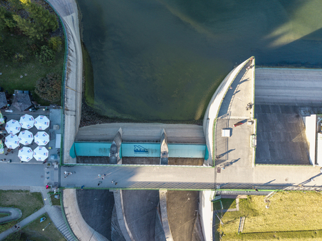 Niedzica Poland 19 September 2026 Aerial view of Czorsztyn Dam with its concrete structure surrounding water and people walking on the bridge under clear sky.