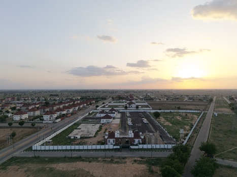 Aerial view of modern residential buildings with red roofs and a large parking area under a golden sunset sky in Kano Kano Nigeria.