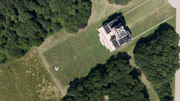 Aerial view of Thiepval Memorial to the Missing of the Somme surrounded by manicured lawns rows of grave markers and dense woodland in Thiepval Hauts de France France.