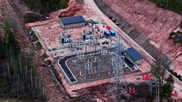 Aerial view of an electrical substation with transformers and power lines situated in a rural area surrounded by forest and red soil in Latvia. Aerial view of an electrical substation with transformers and power lines situated in a rural area surrounded by forest and red soil in Latvia.