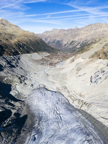 Aerial view of the stark white glacier tongue winding through the rugged valley framed by the golden hues of the mountains Morteratsch Glacier Grisons Switzerland. Aerial view of the stark white glacier tongue winding through the rugged valley framed by the golden hues of the mountains Morteratsch Glacier Grisons Switzerland.