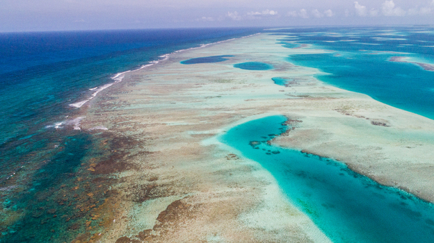 Aerial view of the Los Roques archipelago featuring vibrant turquoise waters shallow coral reefs and deep blue ocean expanses in Los Roques Dependencias Federales Venezuela. Aerial view of the Los Roques archipelago featuring vibrant turquoise waters shallow coral reefs and deep blue ocean expanses in Los Roques Dependencias Federales Venezuela.