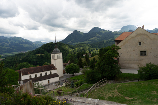 Gruyeres Switzerland 14 May 2026 View of the Eglise de Gruyeres church and historic buildings against a backdrop of lush green mountains under a cloudy sky. Gruyeres Switzerland 14 May 2026 View of the Eglise de Gruyeres church and historic buildings against a backdrop of lush green mountains under a cloudy sky.