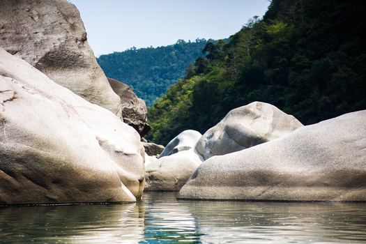 Meghalaya India 31 March 2023 View of large smooth river rocks in a river with lush green hills in the background. Meghalaya India 31 March 2023 View of large smooth river rocks in a river with lush green hills in the background.