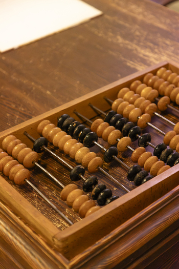 View of a traditional wooden abacus with rows of light brown and black beads resting on a rustic wooden table in Gdansk Pomeranian Voivodeshi Poland. View of a traditional wooden abacus with rows of light brown and black beads resting on a rustic wooden table in Gdansk Pomeranian Voivodeshi Poland.