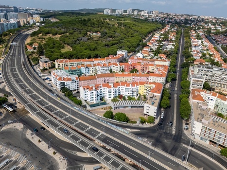 Aerial view of the residential district with colorful buildings a highway and lush green parkland in Alges Lisbon Portugal.