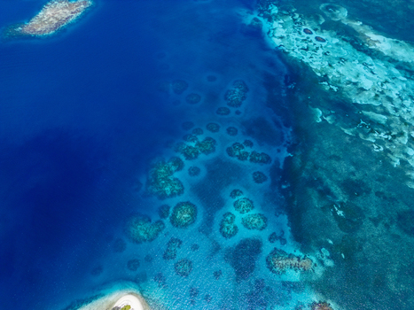 Aerial view of vibrant coral reefs and turquoise waters surrounding the tropical island of Guanaja Bay Islands Department Honduras. Aerial view of vibrant coral reefs and turquoise waters surrounding the tropical island of Guanaja Bay Islands Department Honduras.