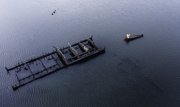 Aerial view of a rusted shipwreck partially submerged in calm blue water United States. Aerial view of a rusted shipwreck partially submerged in calm blue water United States.