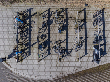 Aerial view of bicycles neatly parked in a structured rack casting long shadows on the patterned pavement Delft Netherlands. Aerial view of bicycles neatly parked in a structured rack casting long shadows on the patterned pavement Delft Netherlands.