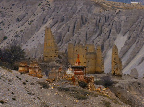 Aerial view of ancient stone chortens and ruins nestled in the dramatic eroded landscape of the Himalayas in Nepal.