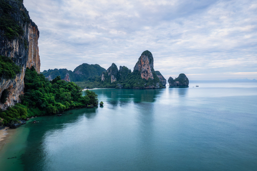 Aerial view of Railay Beach featuring dramatic limestone cliffs lush greenery and calm turquoise waters in Ao Nang Krabi Thailand. Aerial view of Railay Beach featuring dramatic limestone cliffs lush greenery and calm turquoise waters in Ao Nang Krabi Thailand.