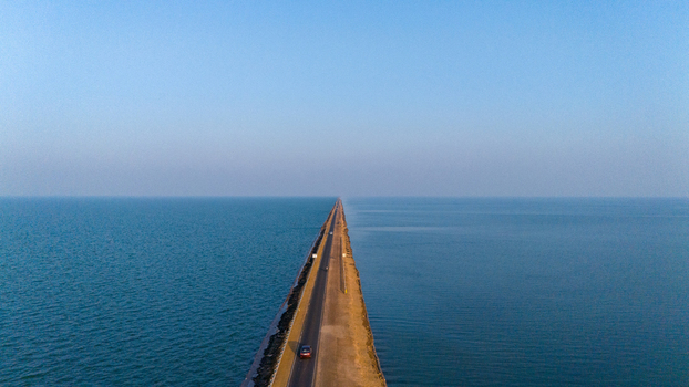 Aerial view of the Road to Heaven stretching across the vast blue waters of the Rann of Kutch with a single car driving along the narrow asphalt road in Bhuj Gujarat India. Aerial view of the Road to Heaven stretching across the vast blue waters of the Rann of Kutch with a single car driving along the narrow asphalt road in Bhuj Gujarat India.