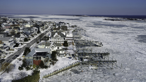 Aerial view of the coastal town of Highlands in winter featuring snow covered houses frozen bay waters and wooden docks along the shoreline in Highlands New Jersey United States. Aerial view of the coastal town of Highlands in winter featuring snow covered houses frozen bay waters and wooden docks along the shoreline in Highlands New Jersey United States.