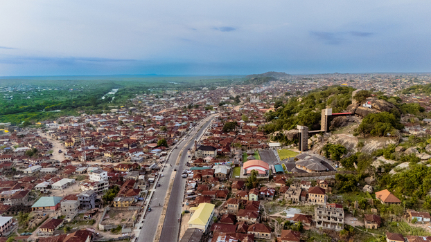 Aerial view of rooftops and a sprawling city blending into the horizon with a prominent rock formation rising above the landscape Ibadan Nigeria. Aerial view of rooftops and a sprawling city blending into the horizon with a prominent rock formation rising above the landscape Ibadan Nigeria.