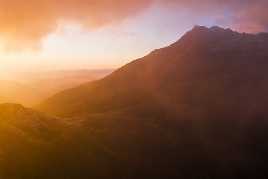 Aerial view of the rugged mountain peaks of Cerreto Laghi enveloped in golden mist and warm sunset light Cerreto Laghi Emilia Romagna Italy. Aerial view of the rugged mountain peaks of Cerreto Laghi enveloped in golden mist and warm sunset light Cerreto Laghi Emilia Romagna Italy.