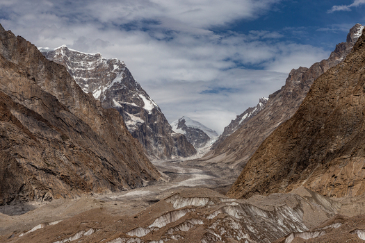 View of Baltoro Glacier surrounded by rugged mountain peaks rocky moraine and snow capped summits under a cloudy sky Baltoro Gilgit Baltistan Pakistan.