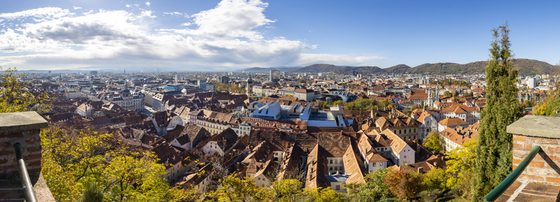 View of warm terracotta rooftops cascading across the cityscape under a bright sky framed by autumn foliage and brick structures Graz Styria Austria. View of warm terracotta rooftops cascading across the cityscape under a bright sky framed by autumn foliage and brick structures Graz Styria Austria.
