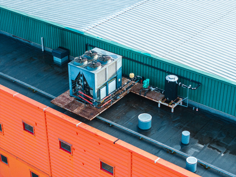 Aerial view of an industrial HVAC chiller unit installed on a flat rooftop with orange and green metal walls in Riga Latvia. Aerial view of an industrial HVAC chiller unit installed on a flat rooftop with orange and green metal walls in Riga Latvia.
