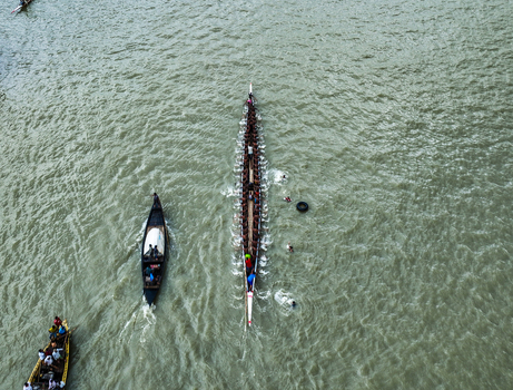 Baghabari Rajshahi Division Bangladesh 20 August 2022 Aerial view of a traditional long boat race with rowers paddling in unison on the river with support boats nearby.