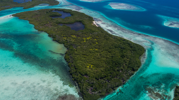 Aerial view of Los Roques archipelago featuring lush green vegetation and inland lagoons surrounded by vibrant turquoise shallow waters and deep blue sea in Los Roques Dependencias Federale Venezuela. Aerial view of Los Roques archipelago featuring lush green vegetation and inland lagoons surrounded by vibrant turquoise shallow waters and deep blue sea in Los Roques Dependencias Federale Venezuela.