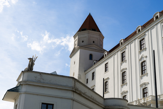 View of the white facade and red tiled tower of Bratislava Castle under a bright blue sky in Bratislava Bratislava Region Slovakia. View of the white facade and red tiled tower of Bratislava Castle under a bright blue sky in Bratislava Bratislava Region Slovakia.