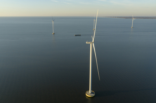 Aerial view of offshore wind turbines standing in calm blue water under a clear sky during golden hour Netherlands. Aerial view of offshore wind turbines standing in calm blue water under a clear sky during golden hour Netherlands.