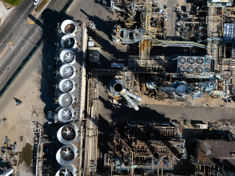 Aerial view of an industrial oil refinery featuring large cooling towers complex piping systems and storage tanks in Carson California United States.