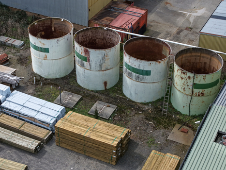Melbourne Australia 25 September 2026 Aerial view of four large industrial storage tanks surrounded by stacks of timber and construction materials in a factory yard.