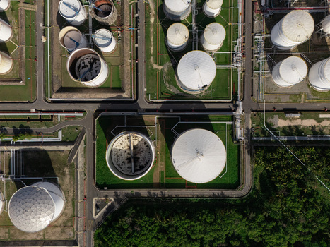 Aerial view of industrial oil storage tanks with white circular structures pipeline networks and surrounding green vegetation in Bajos de Haina San Cristobal Province Dominican Republic.