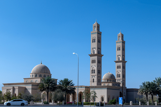 View of a modern mosque with two tall minarets and domes under a clear blue sky in Muscat Muscat Governorate Oman. View of a modern mosque with two tall minarets and domes under a clear blue sky in Muscat Muscat Governorate Oman.