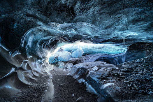 View of the interior of an ice cave with translucent blue ice walls and textured frozen surfaces in Vatnajokull National Park Iceland. View of the interior of an ice cave with translucent blue ice walls and textured frozen surfaces in Vatnajokull National Park Iceland.