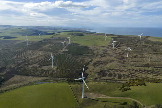 Aerial view of a windfarm with white turbines on rolling hills overlooking the sea in Scotland United Kingdom. Aerial view of a windfarm with white turbines on rolling hills overlooking the sea in Scotland United Kingdom.