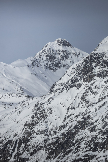 View of majestic snow covered mountain peaks with rugged rocky slopes under a clear winter sky in Ersfjord Troms Norway. View of majestic snow covered mountain peaks with rugged rocky slopes under a clear winter sky in Ersfjord Troms Norway.