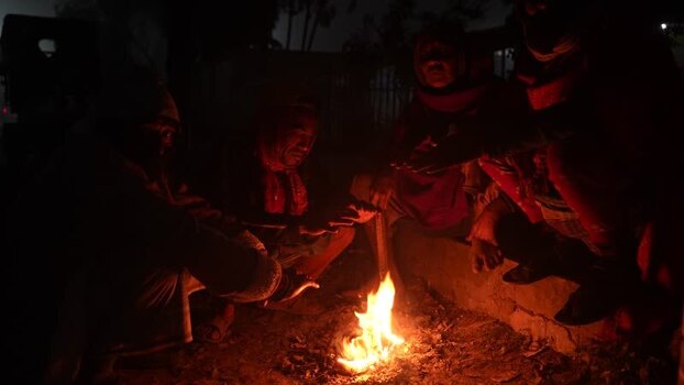 View of people warming themselves by a fire at night Bangladesh. View of people warming themselves by a fire at night Bangladesh.