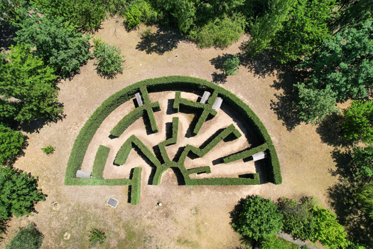 Aerial view of a semi circular hedge maze surrounded by lush green trees and dry grass in a park in Turin Piedmont Italy. Aerial view of a semi circular hedge maze surrounded by lush green trees and dry grass in a park in Turin Piedmont Italy.