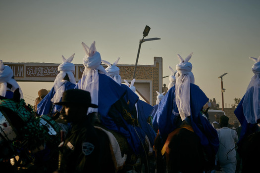 Zaria city Nigeria 22 March 2026 View of a vibrant procession of horsemen in striking blue and white attire moving under a soft golden sky. Zaria city Nigeria 22 March 2026 View of a vibrant procession of horsemen in striking blue and white attire moving under a soft golden sky.
