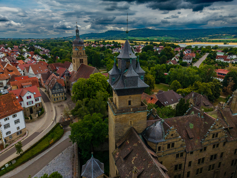 Aerial view of the historic Neuenstein Castle with its distinctive towers and red tiled roofs surrounded by the charming townscape and lush greenery in Neuenstein Baden Wurttemberg Germany. Aerial view of the historic Neuenstein Castle with its distinctive towers and red tiled roofs surrounded by the charming townscape and lush greenery in Neuenstein Baden Wurttemberg Germany.