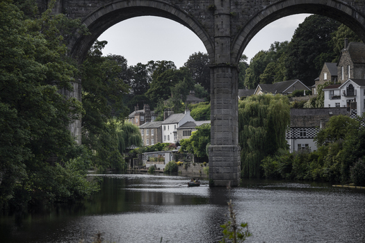 View of the historic Knaresborough Viaduct spanning the River Nidd with lush trees and stone buildings in Knaresborough England United Kingdom.
