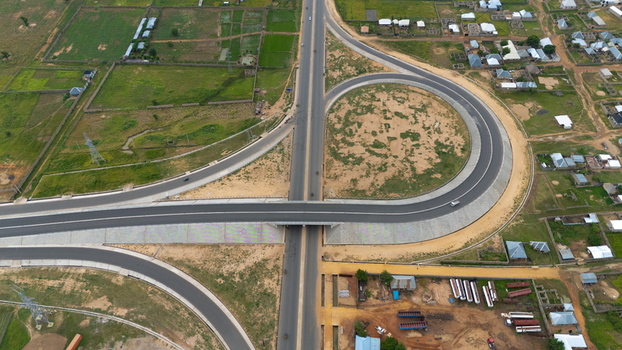 Aerial view of a modern highway interchange with curved ramps and asphalt roads surrounded by rural landscape and residential buildings in Yola Adamawa Nigeria. Aerial view of a modern highway interchange with curved ramps and asphalt roads surrounded by rural landscape and residential buildings in Yola Adamawa Nigeria.