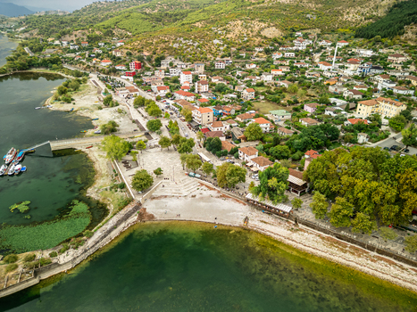 Aerial view of the village of Shiroka on the shore of Lake Shkoder featuring a stone paved waterfront square residential houses and lush trees in Shiroka Shkoder County Albania.