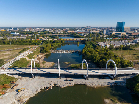 Aerial view of the modern bridge with white circular arches spanning the White River surrounded by greenery and urban infrastructure in Indianapolis Indiana United States. Aerial view of the modern bridge with white circular arches spanning the White River surrounded by greenery and urban infrastructure in Indianapolis Indiana United States.